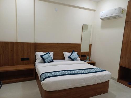 a bedroom with a bed with blue and white pillows at Hotel Soni Indore in Indore