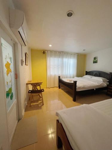 a room with two beds and a table in it at Moradok Thai Guesthouse in Phra Nakhon Si Ayutthaya
