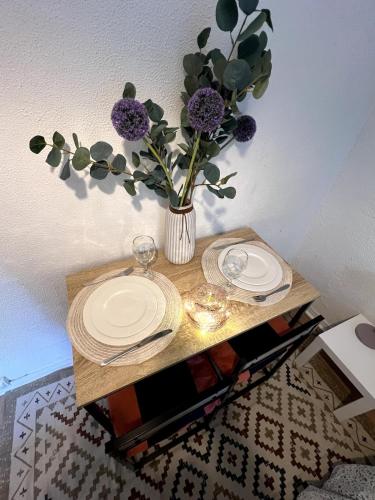 a table with two plates and a vase with purple flowers at Studio Cozy in Larue