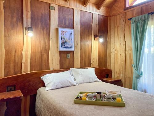 a bedroom with a bed with a tray of food on it at CABAÑAS RACO in Licán Ray