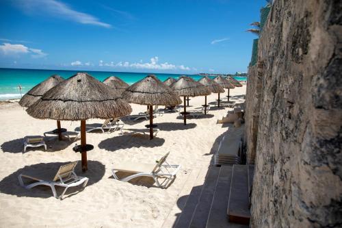 a row of straw umbrellas and chairs on a beach at BeachView & Balcony 3905 in Cancún