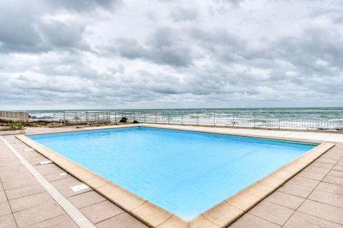 een groot zwembad met de oceaan op de achtergrond bij Premium Ocean View Studio, Balcony & Pool in Les Sables-dʼOlonne
