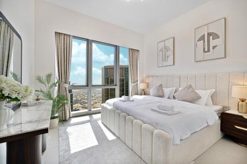 a white bedroom with a large bed and a large window at Luxury 2BR Sea Burj views Khalifa infinity pool in Dubai