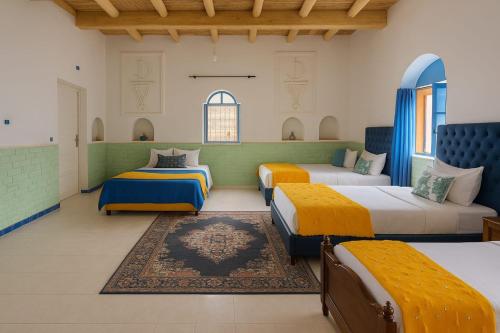 1 dormitorio con 3 camas y alfombra en Grotte Salwa, en Aït Ben Haddou