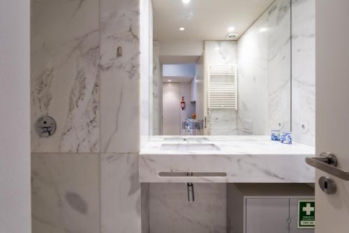 a white bathroom with a sink and a mirror at Host Wise - Modern Stuning Flat w Prime Location in Porto