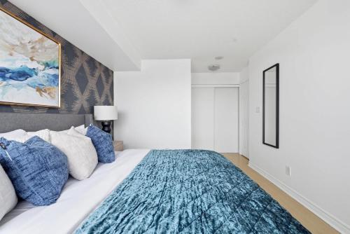 Un dormitorio con una cama grande con almohadas azules. en Stylish 2br High-Rise - Sleeps 7 - YYZ, en Mississauga