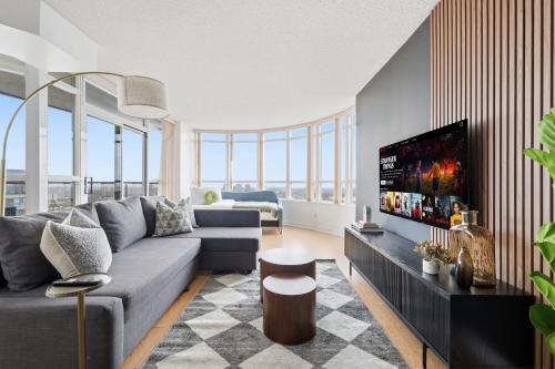 Una sala de estar con un sofá y un televisor de pantalla plana. en Stylish 2br High-Rise - Sleeps 7 - YYZ, en Mississauga