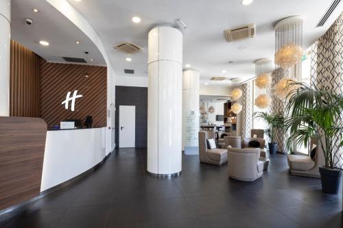 a lobby with chairs and a bar in a building at Holiday Inn Genoa City by IHG in Genoa