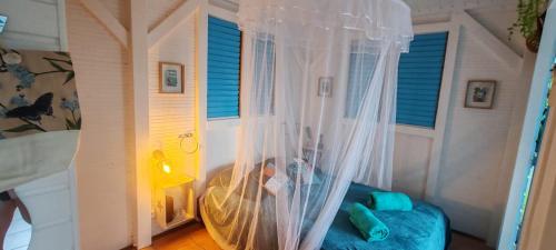 a bedroom with a bed and a window with curtains at Bungalow Carambole - Bleu des Iles vue mer in Deshaies