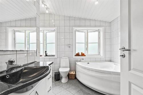 Un baño blanco con bañera y inodoro. en 3670-Nexo-Odden-11, en Bedegård