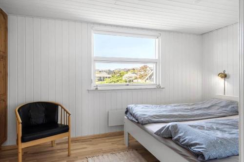 a bedroom with a bed and a chair and a window at G421-Lemvig-Gyvelvej-21 in Lemvig