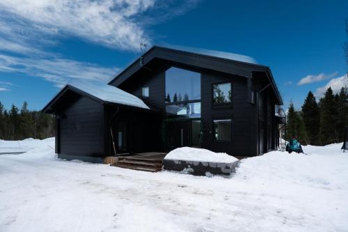 Ein schwarzes Haus im Schnee im Schnee in der Unterkunft Serenity Levi - Hot Tub & Sauna in Levi