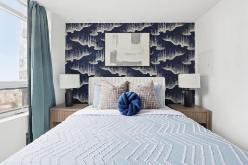Designer 2BR - King Suite - Rare 2 Parking - YYZ في ميسيساوغا: غرفة نوم عليها سرير ومخدة زرقاء