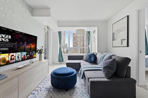 a living room with a couch and a tv at Designer 2BR - King Suite - Rare 2 Parking - YYZ in Mississauga