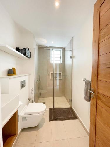 a bathroom with a toilet and a glass shower at Ocean Point Beachfront 3-Bedroom Suites by LOV Mauritius in Pointe aux Piments