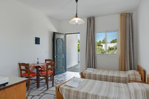 Una habitación de hotel con dos camas, una mesa y un escritorio. en Ilios and Irene 4, en Mastichari