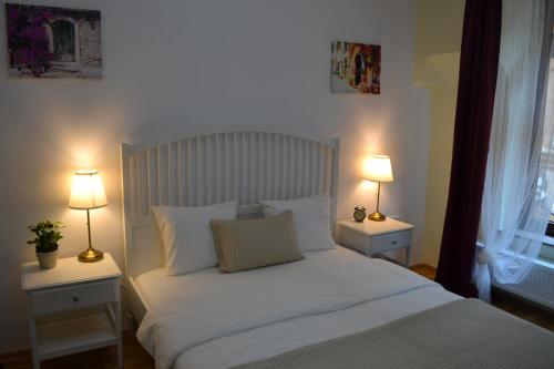 a bedroom with a white bed with two lamps at Casa Krone - Piața Sfatului in Braşov
