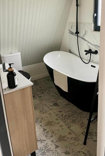 a bathroom with a black and white bath tub at Lodge Lady Tipi 2 avec jacuzzi et piscine in Saint-Utin
