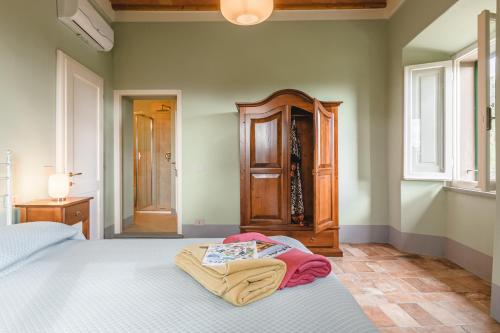 a bedroom with a bed and a wooden cabinet at Dimora Vecchio Duomo - Together in Tuscany in Cortona