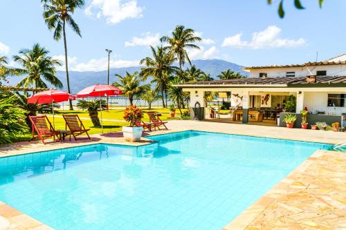 a swimming pool with chairs and umbrellas next to a house at VELINN Hotel Guarda Mor in São Sebastião