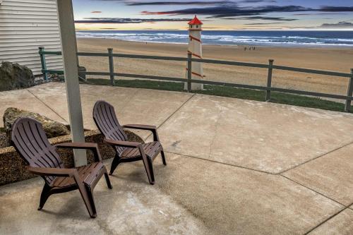 two chairs sitting next to a lighthouse on the beach at Oceanfront Studio - Ground Floor - Sleeps 4 in Lincoln City