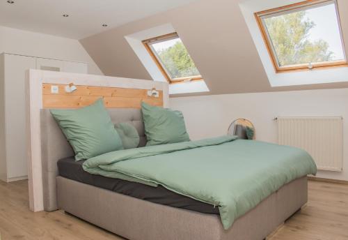 a bedroom with a bed with green sheets and windows at Green& Light House16 in Kettenis