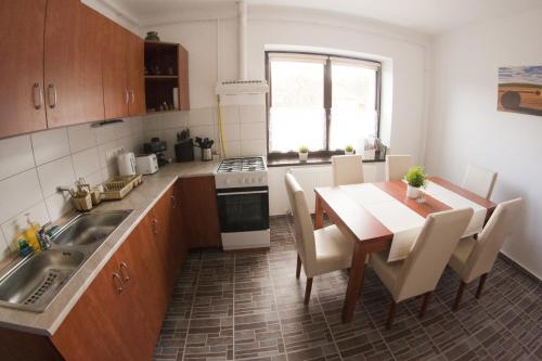 a kitchen with a table and a sink and a table and chairs at Macskakő Vendégház in Somoskőújfalu