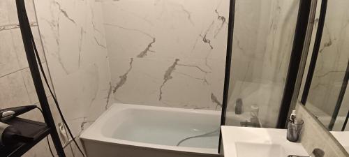a bathroom with a white tub and a marble shower at Lit en dortoir pour homme chez l'habitant au Kremlin-Bicêtre in Le Kremlin-Bicêtre