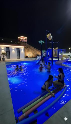 a group of people in a swimming pool at night at شاليه جوري حتا-4-Chalet Jory Hatta in Būbādī