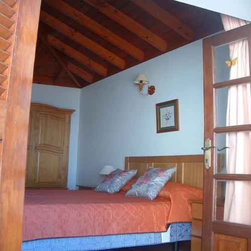 a bedroom with a bed with orange sheets and blue pillows at Casa Los Viñedos A in Fuencaliente de la Palma