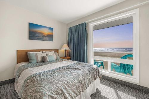 a bedroom with a bed and a large window at Pool and Hot Tub Ground Floor Studio - Oceanfront - Full Kitchen - Patio in Lincoln City