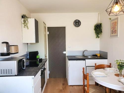 a small kitchen with a table and a microwave at Au Bord De L'eau, Proche plages in Saint-Jean-de-Monts