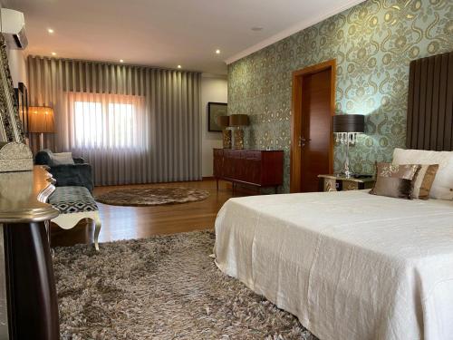 a bedroom with a bed and a living room at Camélias Casa de Charme in Varziela