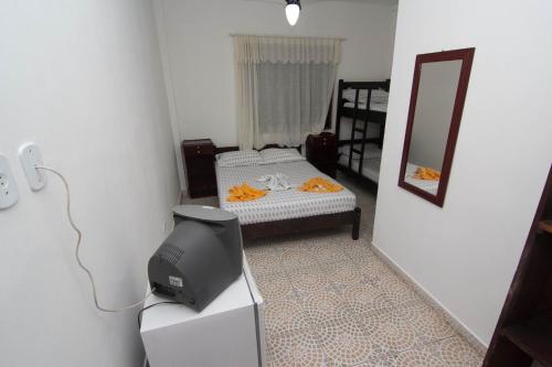 a small bedroom with a bed and a mirror at Hotel Águas Vivas in Caraguatatuba