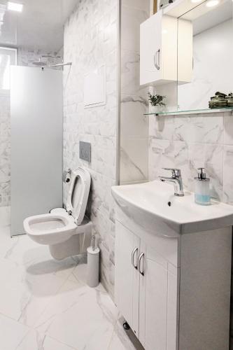 a white bathroom with a toilet and a sink at Cozy and Stylish Apartment 2 in Stara Zagora