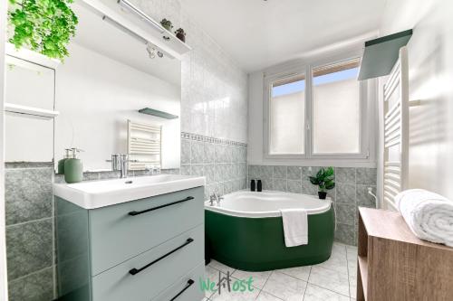 ピエール・ベニットにあるREPUBLIQUE - LYON 2 - KP - Lumineux et chaleureux T3 aux portes de Lyonのバスルーム(緑のバスタブ、シンク付)