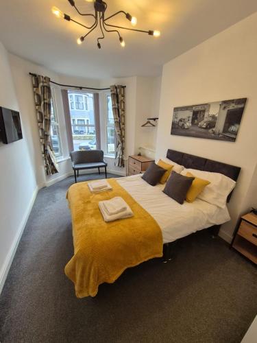 a bedroom with a large bed with a yellow blanket at Lovely refurbished apartments, Morecambe Promenade in Morecambe