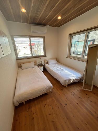 青森グッドタイム旭町的有两张床的房间有两扇窗户