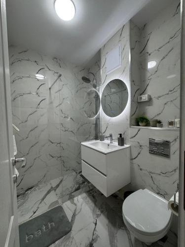 a bathroom with a white toilet and marble walls at Panoramic SkyView Apartment in Petroşani