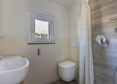 a bathroom with a sink and a toilet and a window at Bilocale Pianosa - riservato e fresco a soli 10 m dal mare in Pomonte