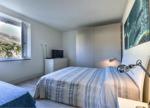 a white bedroom with a bed and a window at Bilocale Pianosa - riservato e fresco a soli 10 m dal mare in Pomonte