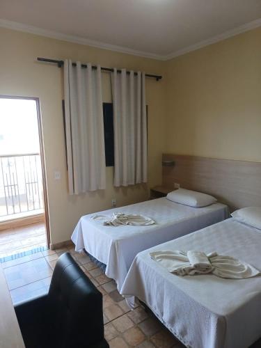 a hotel room with two beds and a window at Hotel Inter Alexandria in Cândido Mota