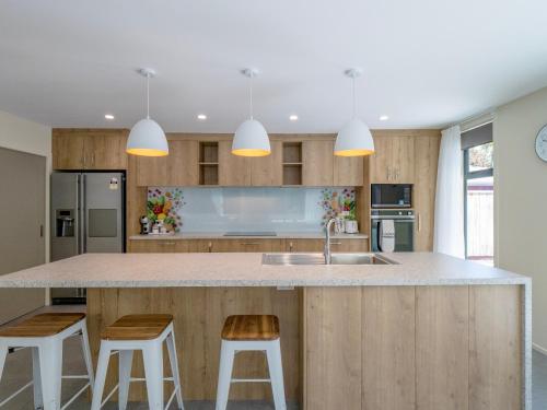 a kitchen with a large island with two bar stools at Architectural Retreat in Prestigious Whanganui in Whanganui
