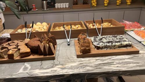 a table with several different types of cakes and pastries at Vox Hotel in São João de Meriti