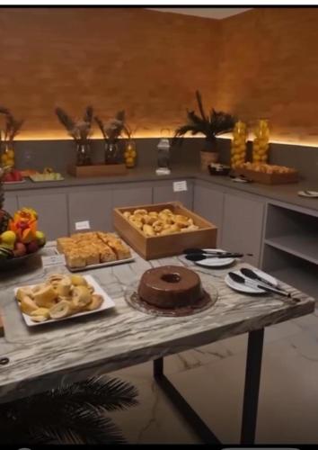 a table with a cake and other food on it at Vox Hotel in São João de Meriti