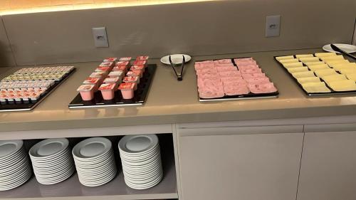 a counter with many different types of cakes and pastries at Vox Hotel in São João de Meriti