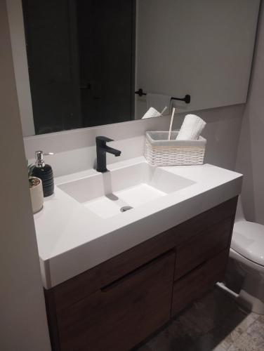 Un baño con un lavabo con espejo y un inodoro. en Brand New Modern Apartment-Suite Meters from the Beach, en Gaira
