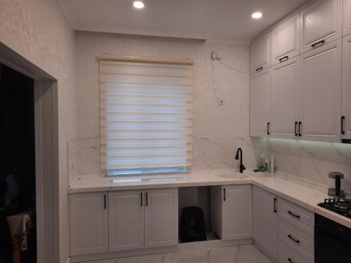 Una cocina con gabinetes blancos y una ventana. en Уютный дом для семьи AL INN, en Qusar