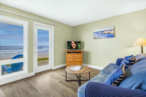 a living room with a blue couch and a tv at Oceanfront Studio - Ground Floor - King Bed - Easy Beach Access - Pool & Hot Tub in Lincoln City