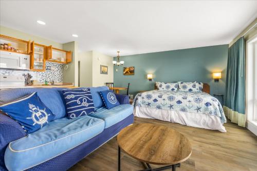 a living room with a blue couch and a bed at Oceanfront Studio - Ground Floor - King Bed - Easy Beach Access - Pool & Hot Tub in Lincoln City